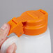A person holding a Tablecraft plastic dispenser jar with an orange lid.