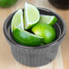 A Tablecraft natural cast aluminum souffle bowl filled with lime slices on a counter.