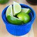 A blue Tablecraft cast aluminum souffle bowl filled with limes and lime slices.