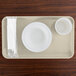 A Cambro rectangular white fiberglass tray with a bowl and cup on a wood surface.