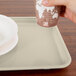 A hand holding a cup over a Cambro white rectangular tray.