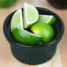 A Tablecraft hunter green cast aluminum souffle bowl filled with limes on a counter.