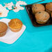 A plate of muffins on a blue table with a Bermuda blue table cover.