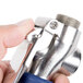 A hand holding a silver and blue metal T&S EB-0108-H spray valve.