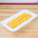 A white rectangular Carlisle food pan with macaroni and cheese on a wood surface.