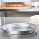 An American Metalcraft aluminum deep dish pizza pan on a counter with a ball of dough.