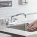 A person washing their hands under a Regency Deck Mount Bar Faucet.