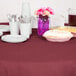 A table set with burgundy Creative Converting OctyRound tablecloths, plates, and cups.