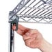A hand using a screw to attach a metal shelf to a Metro Super Erecta wire shelving unit.