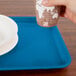 A hand holding a cup over a blue tray.