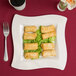 A Fineline bone plastic square plate with fried spring rolls and a fork.