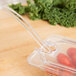 A Carlisle clear plastic food pan lid with a spoon notch on a plastic container with a spoon in it.