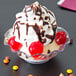 A Carlisle clear tulip bowl filled with ice cream, chocolate syrup, and cherries.