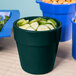 A Hunter green Tablecraft condiment bowl filled with cucumbers and croutons on a table with other food.