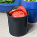 A black Tablecraft cast aluminum condiment bowl with sliced tomatoes in it.