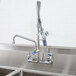 A stainless steel sink with a T&S EasyInstall wall mounted pre-rinse faucet above it.