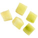 A group of green and yellow fruit cubes on a white surface.