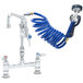 A T&S pet grooming faucet with a blue coiled hose and aluminum spray valve.