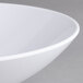 A close-up of a white Carlisle melamine vegetable bowl with a rim.