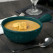A Tablecraft hunter green cast aluminum soup bowl with croutons and a spoon.