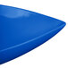 A Tablecraft cobalt blue cast aluminum triangle display bowl with a curved edge and blue corner.