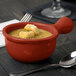 A Tablecraft copper cast aluminum soup bowl with a handle filled with soup on a table with a spoon.