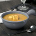 A Tablecraft gray cast aluminum soup bowl with a handle filled with soup and croutons.