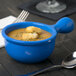 A blue Tablecraft cast aluminum bowl of soup with croutons and a spoon.