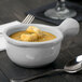 A Tablecraft natural cast aluminum soup bowl with a handle filled with soup and croutons with a spoon next to it.