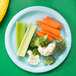 A pastel blue Creative Converting paper plate with carrots and broccoli on it.