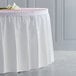 A white Creative Converting plastic table skirt on a table.
