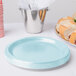 A stack of pastel blue paper plates on a table with food and punch.