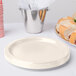 A stack of ivory paper plates with a plate and a bucket of food on one of the plates.