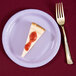 A piece of cheesecake on a Creative Converting Luscious Lavender paper plate with a fork.