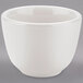 A Tuxton white china sake tea cup on a gray surface.