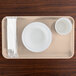 A light peach rectangular Cambro tray with a white bowl and cup on it.