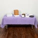 A table with a Creative Converting Luscious Lavender Purple tablecloth and food on it.