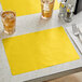 A table set with a glass of iced tea on a gold scalloped paper placemat.