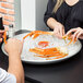 A woman and man eating crab legs on an American Metalcraft aluminum seafood tray on a table.