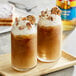 Two glasses of brown liquid flavored with Torani English Toffee syrup, topped with whipped cream and nuts.