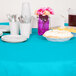 A table set with Bermuda Blue OctyRound tablecloths, plates, and white cups with silverware.