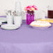 A table set with plates and cups covered with a purple table cover.