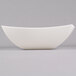A Fineline ivory plastic serving bowl with a wavy edge on a gray surface.