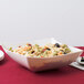 A Fineline Wavetrends ivory plastic serving bowl filled with pasta salad on a table.