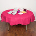 A table with a pink Creative Converting table cover, plates, and cups set up for a party.