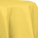 A Creative Converting Mimosa Yellow OctyRound tablecloth with a white border on a table.
