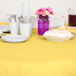 A table with Creative Converting Mimosa Yellow table covers, plates, and cups set up for a meal.