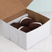 A white bakery box filled with chocolate cookies.