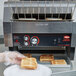 A person putting toast on a plate using a Hatco TQ-1800 conveyor toaster.