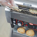A person holding a tray of bread over a Hatco Toast Qwik Conveyor Toaster.